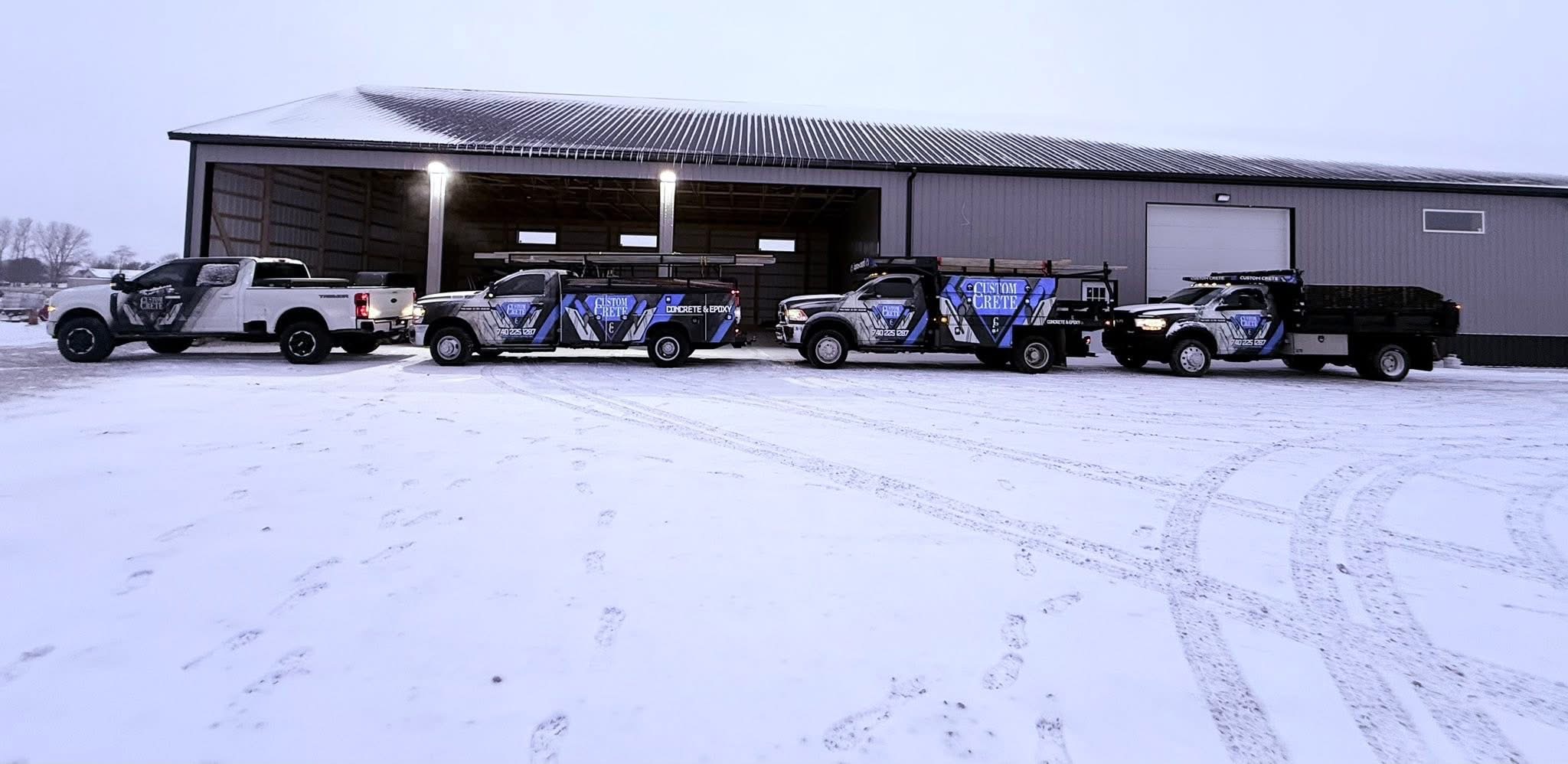 Custom Crete branded truck fleet parked in front of the company shop on a snowy winter day