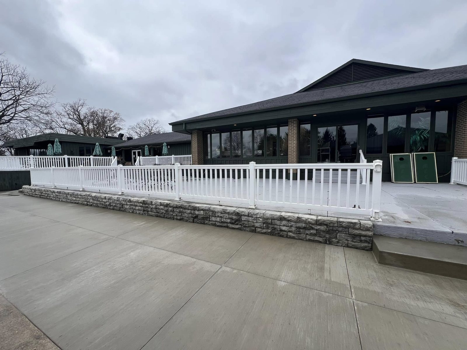 Wide broom-finished concrete patio and deck with white railing at a clubhouse.