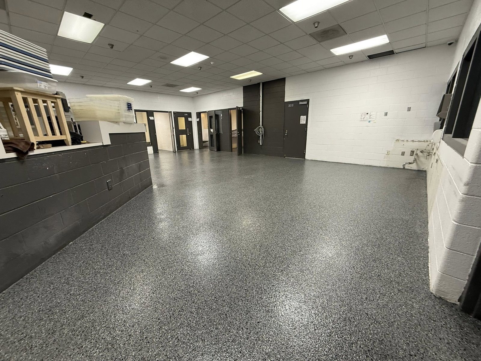 Glossy gray flake epoxy floor in a large facility common area.