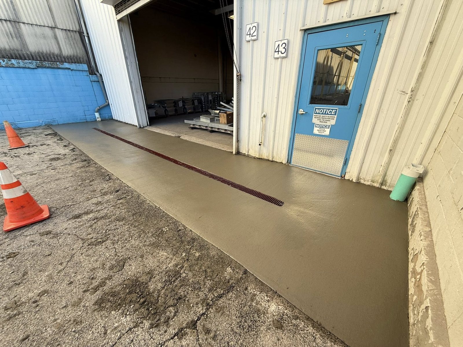 Finished concrete loading-dock apron with an inset trench drain at a warehouse.