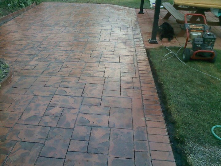 Stamped concrete patio in an ashlar slate pattern with terracotta and brown coloring and a brick-pattern border.