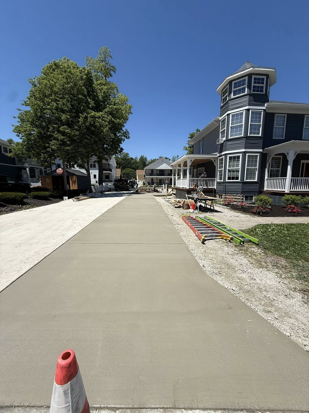 Wide fresh broom-finished concrete driveway running between two homes.